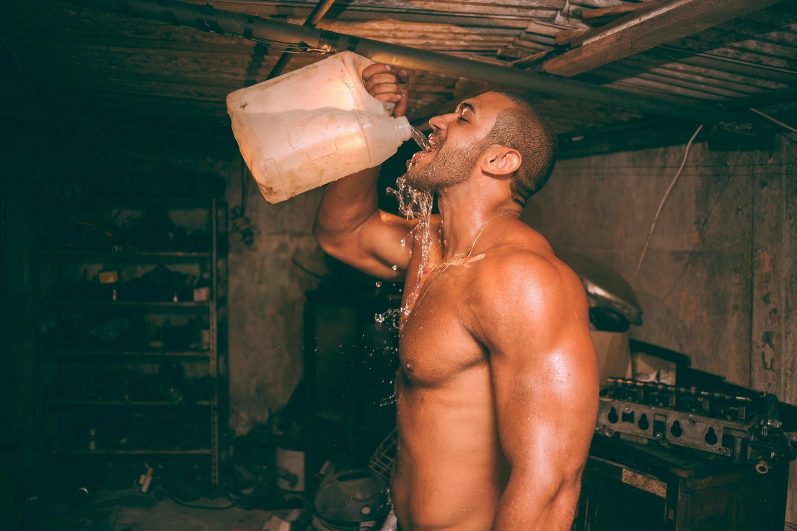 topless man drinking water from plastic container